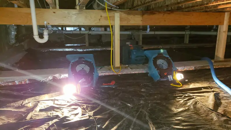 Air movers and plastic sheeting in a crawl space under floor joists