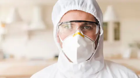 Person in a protective hood, goggles and N95 mask